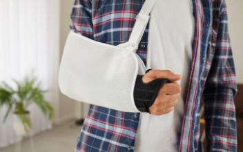 Nahaufnahme des Arms eines Mannes mit Stützkorsett und Schlingentuchverband nach einer Unfallverletzung
