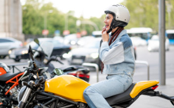 Frau auf gelbem Motorrad setzt sich ihren Motorradhelm auf