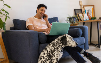 Mann telefoniert auf seinem Sofa, zu seinen Füßen sitzt ein Dalmatiner