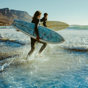 Surfer laufen mit ihren Boards in die Brandung