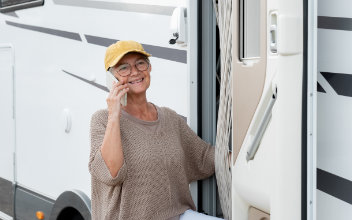 Frau telefoniert mit ihrem Handy vor Wohnmobiltür